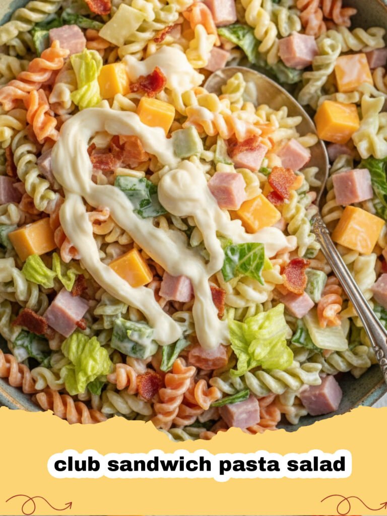 A large bowl of club sandwich pasta salad with visible bacon, turkey, and tomatoes.