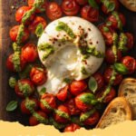 baked burrata roasted tomato - Close-up of warm baked burrata with roasted tomatoes, garlic, and basil in a baking dish, ready to be served.