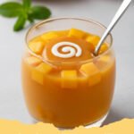 hong kong style mango pudding - Close-up of a perfectly set, vibrant orange Hong Kong style mango pudding garnished with fresh mango cubes and a mint leaf.