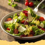 classic italian salad recipe - A vibrant classic Italian salad in a large bowl, featuring crisp lettuce, red onions, tomatoes, cucumbers, olives, and pepperoncinis, with Parmesan cheese sprinkled on top.