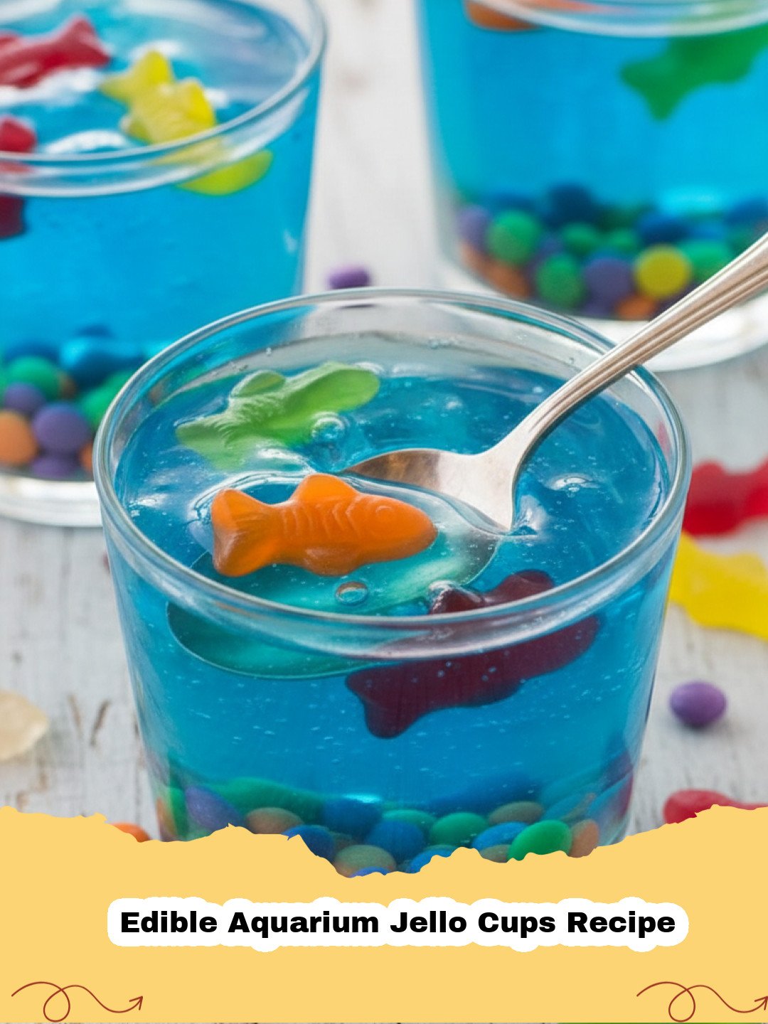 Edible Aquarium Jello Cups Recipe - Vibrant Edible Aquarium Jello Cups filled with gummy fish and blue jello, set against a light background.