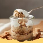 A jar of creamy cinnamon roll overnight oats with a swirl of cream cheese icing on top, garnished with a sprinkle of cinnamon.