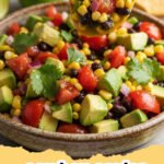 A vibrant bowl of cowboy caviar with tortilla chips and fresh lime wedges