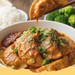 Easy Baked Potstickers Thai Curry Sauce - Close-up of golden baked potstickers swimming in a rich, creamy Thai red curry sauce, garnished with fresh cilantro and green onions.