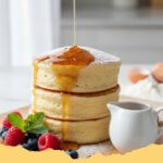 Stack of fluffy, jiggling Cloud Like Japanese Soufflé Pancakes topped with berries and powdered sugar.