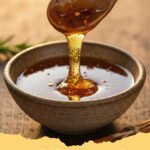 easy hot honey sauce recipe - Homemade easy hot honey sauce in a glass jar with a drizzler, surrounded by red chili flakes.