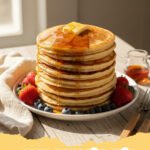 Stack of fluffy homemade pancakes made from easy pancake mix with berries and syrup.
