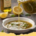 homemade italian dressing - A glass jar of freshly made homemade Italian dressing with fresh herbs and a wooden spoon, ready to be served.