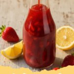strawberry syrup recipe - A vibrant red homemade strawberry syrup in a glass bottle, with fresh strawberries, a lemon, and fluffy pancakes in the background.