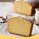 A perfectly baked golden Million Dollar Cream Cheese Pound Cake dusted with powdered sugar, sitting on a wire rack with a slice cut out.