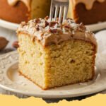 A beautifully frosted Southern Creamy Pineapple Pecan Cake with pecan garnish on a white cake stand.