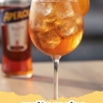 spritz recipe - A perfectly mixed Aperol Spritz in a large wine glass with ice and an orange slice, set against a sunny outdoor background.