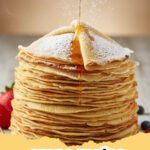 crepe recipe - Stack of perfectly golden-brown French crepes on a white plate, with fresh berries and powdered sugar nearby.