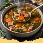 hambone soup recipes - A steaming bowl of hearty hambone soup with vegetables and shredded ham, garnished with parsley and served with a slice of crusty bread.