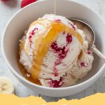 A scoop of creamy cottage cheese ice cream in a bowl, topped with fresh berries and a drizzle of honey.