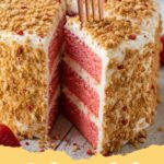 A slice of strawberry crunch cake showing layers of pink cake, white frosting, and a crunchy topping.