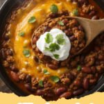 chilli recipe crockpot - A large, bubbling crockpot filled with hearty chilli, garnished with shredded cheese and fresh cilantro, ready to be served.