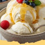 A scoop of creamy cottage cheese ice cream in a bowl, topped with fresh berries and a drizzle of honey.
