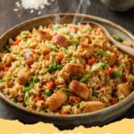 chicken fried rice recipe - Close-up of delicious homemade chicken fried rice with vegetables and scrambled eggs in a wok, garnished with green onions.