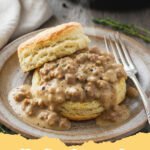biscuits and gravy recipe - Fluffy homemade biscuits smothered in creamy sausage gravy, garnished with fresh parsley.