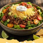 taco salad recipe - A vibrant and fresh beef taco salad in a large bowl, topped with cheese, avocado, and tortilla chips.