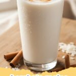 horchata recipe - A tall glass of creamy, authentic Mexican Horchata garnished with a cinnamon stick and a sprinkle of ground cinnamon, surrounded by whole cinnamon sticks and rice grains.