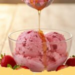strawberry ice cream recipe - A scoop of creamy homemade strawberry ice cream in a white bowl, garnished with fresh strawberries and a mint leaf.
