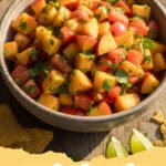 peach salsa recipe - Close-up of a vibrant, fresh peach salsa in a bowl with tortilla chips on the side, ready to be served.