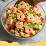 Close-up of a vibrant shrimp ceviche recipe served in a glass bowl with tortilla chips and lime wedges.