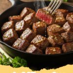 steak bites recipes - Close-up of garlic butter steak bites garnished with parsley in a cast iron skillet