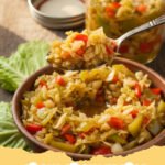 chow chow recipe - A vibrant jar of Southern chow chow relish next to fresh green tomatoes and cabbage.