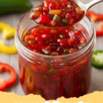 pepper jelly recipe - Several jars of homemade red and green pepper jelly on a wooden board with crackers and cream cheese.