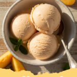 peach ice cream recipe - A close-up of a scoop of creamy homemade peach ice cream in a bowl, garnished with fresh peach slices and a mint sprig.