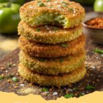 fried green tomatoes recipe - Close-up of golden-brown fried green tomatoes stacked on a wire rack, garnished with fresh parsley.