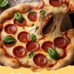 flatbread pizza recipes - Two golden-brown flatbread pizzas topped with melted mozzarella, crumbled goat cheese, roasted red peppers, and fresh green basil leaves on a wooden cutting board.
