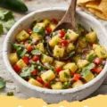 pineapple salsa recipe - A close-up shot of vibrant fresh pineapple salsa in a white bowl, garnished with cilantro, with tortilla chips and a lime wedge in the background.