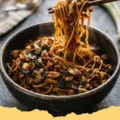 Close-up of Caramelized Scallion Oil Noodles in a bowl, garnished with crispy and fresh green onions.