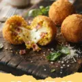 Golden-brown Italian Arancini Rice Balls with ragu and mozzarella, served with marinara sauce.