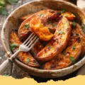Hot Honey Melting Sweet Potatoes garnished with fresh herbs on a white plate.