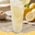 Creamy Lemonade - A tall glass of frosty creamy lemonade with lemon slices and mint on a wooden table outdoors.
