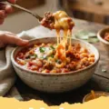 goulash recipes easy - A steaming bowl of homemade beef goulash served with egg noodles and a dollop of sour cream, garnished with fresh parsley.