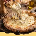 Close-up of a freshly baked Flour + Water Cacio e Pepe Pizza with melted Pecorino Romano and visible black pepper on a golden crust.