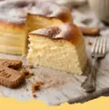 A perfectly golden brown and fluffy Two-Ingredient Japanese Cheesecake on a white plate, dusted with powdered sugar and garnished with fresh berries.
