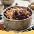 fresh blueberry recipes easy - A close-up shot of a slice of blueberry crumb cake with fresh berries and golden streusel.