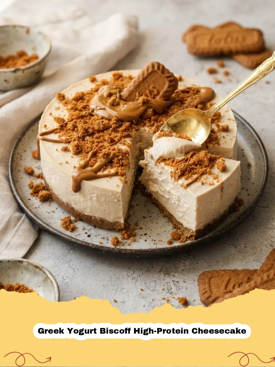 A slice of Greek Yogurt Biscoff High-Protein Cheesecake on a white plate, garnished with crumbled Biscoff cookies and a drizzle of Biscoff spread.