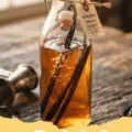 vanilla extract recipe - Two glass bottles of homemade vanilla extract with vanilla beans inside, sitting on a wooden surface.