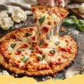A freshly baked Riced Cauliflower Crust Pizza topped with pepperoni and cheese, resting on a wooden board.