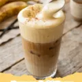 Iced coffee topped with fluffy, light brown Banana Cold Foam, garnished with a banana slice.