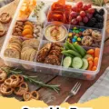 A vibrant and diverse Snackle Box filled with cheese cubes, grapes, crackers, nuts, vegetables, and dip.