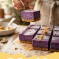 Close-up of Ube Cheesecake Bars on a wooden board, showing the vibrant purple filling and golden crust.